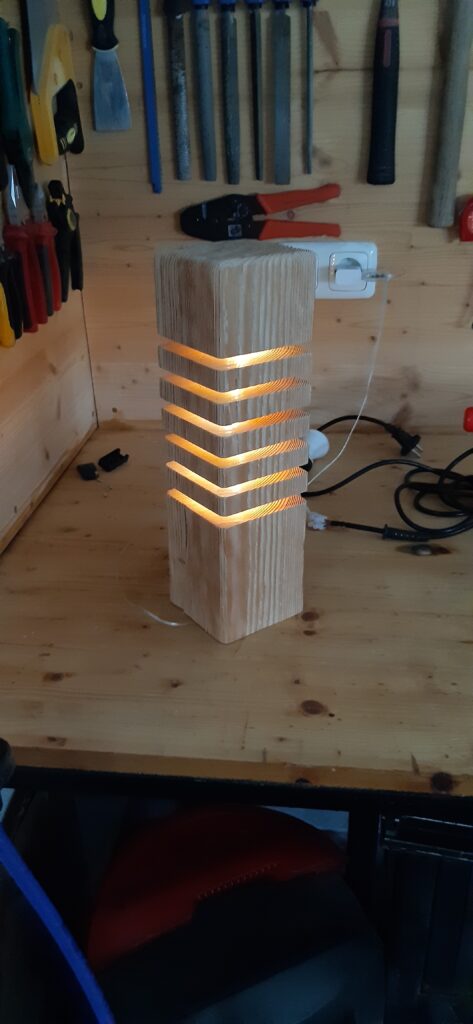 Eine Tischlampe aus Holz, mit Aussparungen am Unteren Ende.